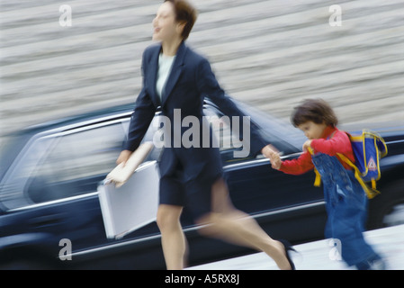 Imprenditrice fretta, tenendo little boy la mano Foto Stock