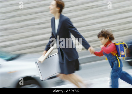 Imprenditrice fretta, tenendo little boy la mano Foto Stock