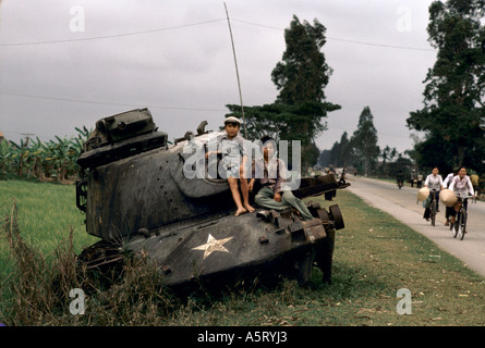 Il Vietnam, lungo l'autostrada 1 tra la tonalità Quang Tri giovani bambini seduti sui resti di un serbatoio AMERICANO 1985 Foto Stock