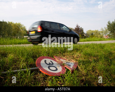 Pericolo di un segno di traffico avvertenza per lavori stradali è avanti giacenti dal lato della strada con una vettura monovolume velocizzando il passato Foto Stock