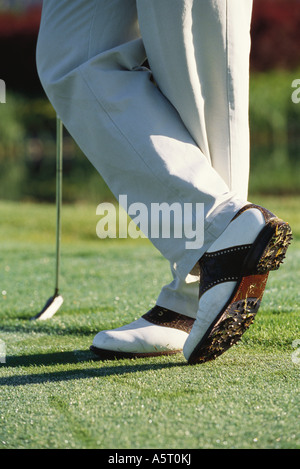 Il Golfer in piedi con le caviglie attraversato, ginocchio verso il basso Foto Stock