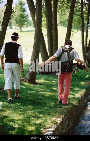 I golfisti in cerca di palla sotto gli alberi, vista posteriore Foto Stock