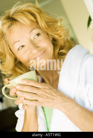 Senior donna che indossa accappatoio e azienda mug Foto Stock