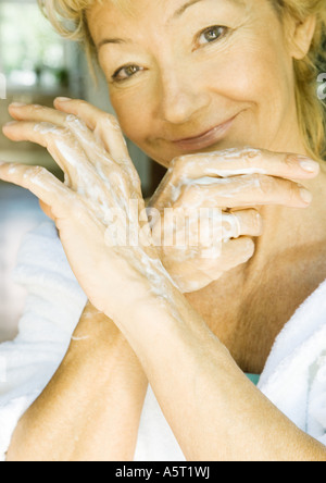 Donna senior di applicare una crema idratante per le mani Foto Stock