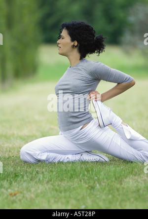 Giovane donna stretching sull'erba Foto Stock