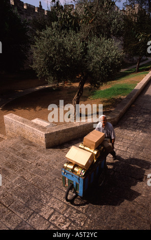Un palestinese con pushcart nella parte anteriore delle mura della città vecchia di Gerusalemme Est Israele Foto Stock
