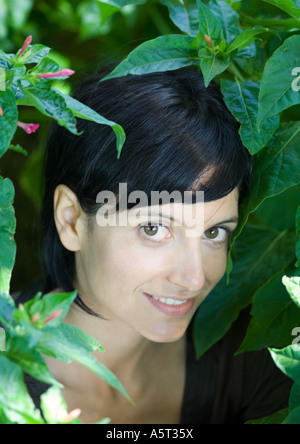 Donna in piedi tra le foglie, testa e spalle Foto Stock