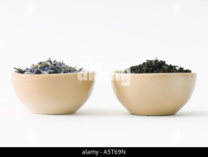 Lavanda essiccata e foglie di tè in ciotole, fianco a fianco Foto Stock