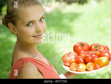 Donna che mantiene ciotola piena di pomodori Foto Stock