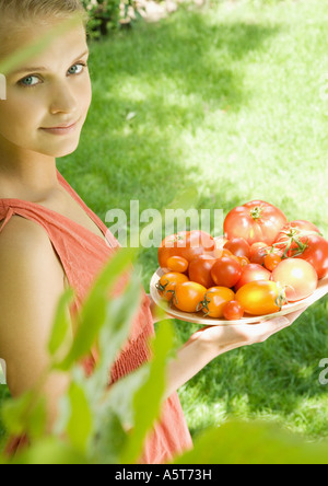 Donna che mantiene ciotola piena di pomodori Foto Stock