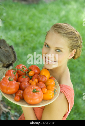 Donna che mantiene ciotola piena di pomodori Foto Stock