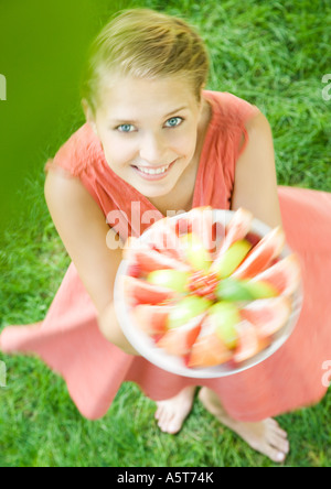 Donna che mantiene fino piatto pieno di fette di frutta e la filatura intorno, ad alto angolo di visione Foto Stock