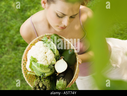 Giovane donna mantenendo la cesta piena di verdure Foto Stock