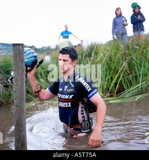 L'uomo che emerge dalla torbiera a bog snorkeling mountain bike competititon sbattevano casco Llanwrtyd Wells Powys Wales UK Foto Stock