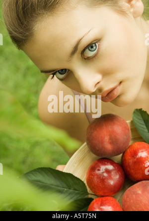 Giovane donna mantenendo la ciotola di pesche e pesche noci Foto Stock