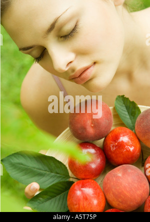 Giovane donna mantenendo la ciotola di pesche e pesche noci Foto Stock