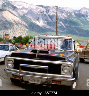 Uomo delle prime Nazioni seduto in un camion di pick-up parcheggiato su Main Street e vista delle Cascade Mountains nella città BC di Lillooet British Columbia Canada Foto Stock