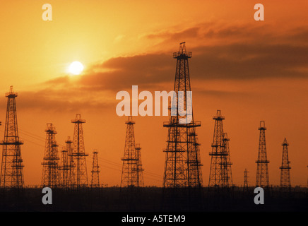 Olio derricks stagliano contro il cielo al tramonto Foto Stock