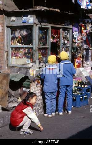 Giovani ragazzi locali si raccolgono intorno ad un piccolo negozio tradizionale vendono dolci caramelle in una piccola strada laterale di Chengdu Cina. Foto Stock