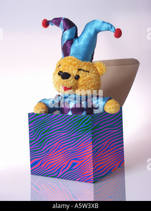 Orsacchiotto in un costume di arlecchino emergente da una scatola Foto Stock
