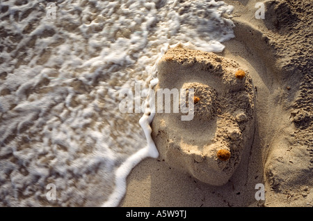 Sandcastle essere lavato via dal mare Foto Stock