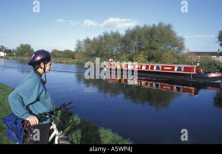 Un ciclista orologi come narrowboat passa vicino a Frampton su Severn su Gloucester nitidezza Canal nel Gloucestershire in Inghilterra Foto Stock