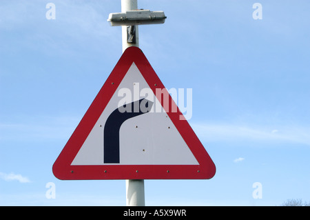 Un triangolo rosso cartello stradale che indica una curva a gomito in avanti su una strada nel Regno Unito Foto Stock