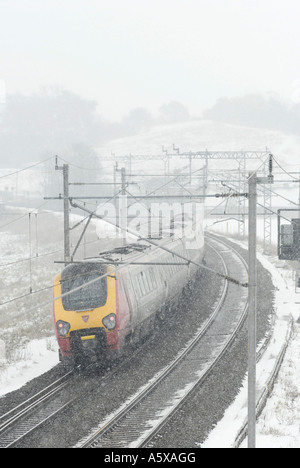 Voyager in treno in treni del Virgin livrea sulla linea principale della costa occidentale verso nord nella neve e nel ghiaccio Inghilterra Foto Stock