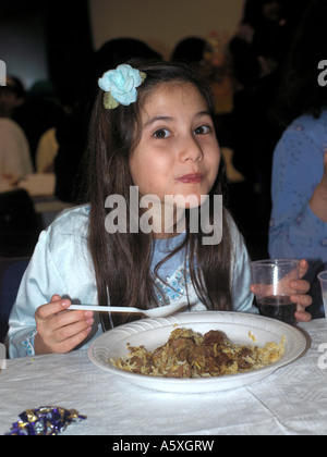 Dieci anni di vecchia ragazza cibo al partito Eid St Josephs Church Hall Epsom Surrey in Inghilterra Foto Stock