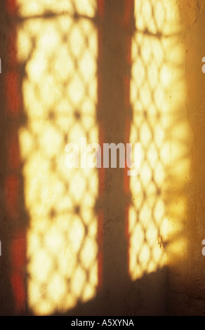 La proiezione di luce calda del diamante due finestre al piombo rosso con vetro macchiato confina con una crema di parete colorata Foto Stock