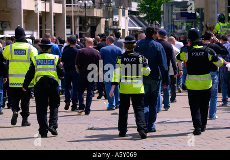 Gli ufficiali di polizia manganelli tracciata vegli su di un gruppo di appassionati di calcio nel centro di Cardiff in città per la finale di FA Cup Foto Stock