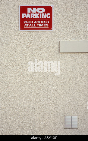 Segno bianco e rosso in alto su una crema verniciato resi parete indicante nessun parcheggio 24 ore di accesso in corrispondenza di tutti i tempi Foto Stock