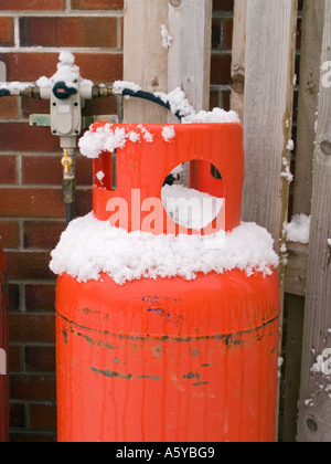 Domestico calor rosso Bottiglia di gas esterno collegato alla valvola regolatrice con neve invernale sul cilindro. Regno Unito Gran Bretagna, Foto Stock