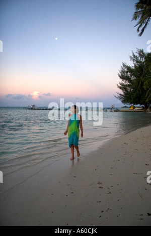 Una donna di camminare sulla spiaggia al tramonto sull'Isola di Moorea Foto Stock