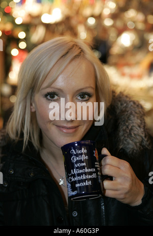 Giovane donna bionda bevendo un vin brulé al mercatino di natale. Foto Stock