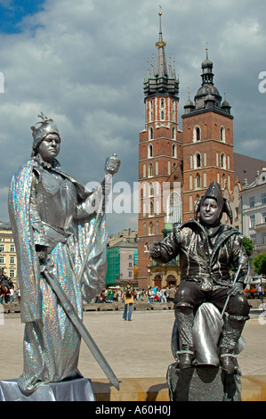 Chiudere verticale fino di artisti di strada in 'Rynek Glowny' Piazza del Mercato con le sue guglie di 'Kosciol Mariacki' St Mary's Church. Foto Stock