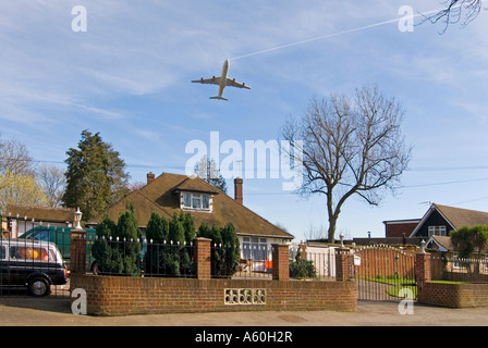 Vista orizzontale di aeromobili in fase di decollo dall'aeroporto di Heathrow, volando a bassa quota sopra case residenziali contro un cielo blu. Foto Stock