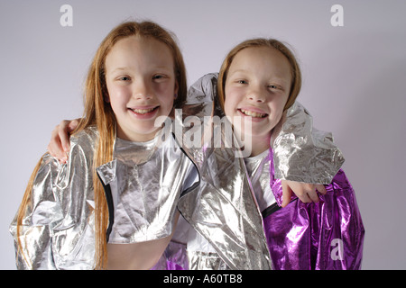 Gemelle età 10 nella sfavillante shiny foil tipo vestiti con bracci intorno a ciascun altro Foto Stock