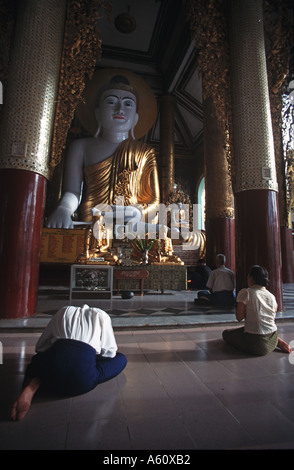 La mattina presto adoratori buddisti pregano in un tempio all'interno di Rangoon s Shwedagon pagoda Birmania complesse Foto Stock