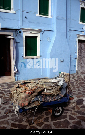 Vecchio carrello contenente le reti da pesca al di fuori di una villa blu sull'isola di Burano, Venezia, Italia. Foto Stock