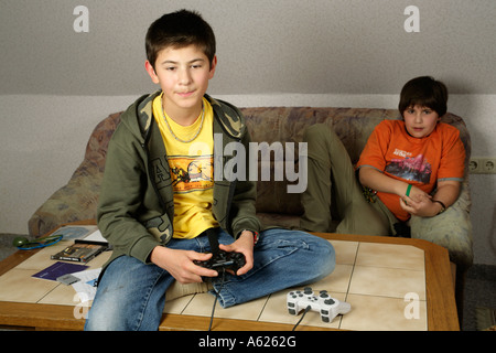 Un giovane ragazzo sta giocando con una pagaia seduto su un tavolo mentre il suo amico sta guardando Foto Stock