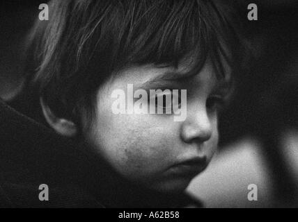 Il grintoso colpo alla testa del piccolo ragazzo che guarda triste e abbattuto Foto Stock