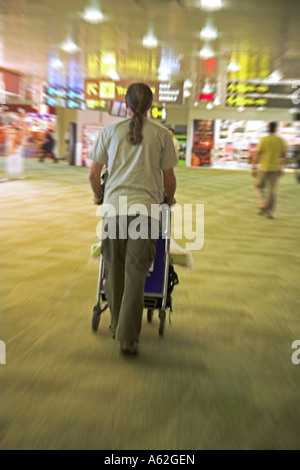 Uomo carrello di spinta attraverso l'Aeroporto Changi di Singapore Foto Stock