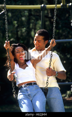 Il nero americano africano giovane nel loro 20s risalente all'aperto su swing relax e divertimento Foto Stock