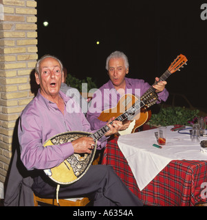 Due uomini locali musicisti di suonare il mandolino e chitarra mentre seduti al ristorante tabella sull'isola di Zante Le Isole greche Foto Stock