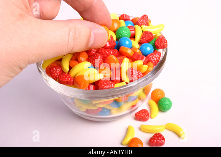 Caramelle in una ciotola con una chiusura su una mano tenendo caramelle Foto Stock