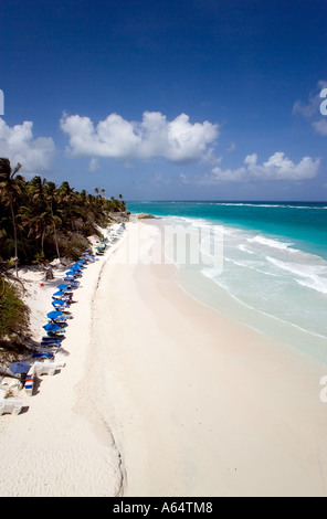WEST INDIES Caraibi Barbados San Filippo parrocchia gru turisti in spiaggia sotto gli ombrelloni in acqua alta linea di spiaggia di sabbia bianca. Foto Stock