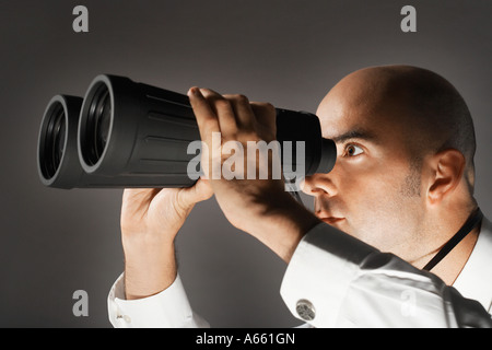 Balding di mezza età imprenditore guardando attraverso il binocolo di grandi dimensioni Foto Stock