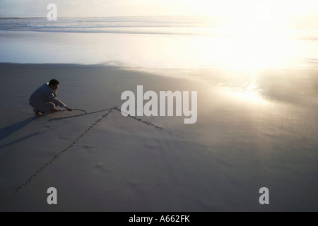 Business man disegno freccia nella sabbia sulla spiaggia, vista in elevazione Foto Stock