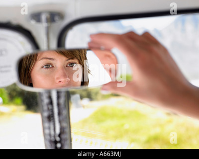 Donna regolazione dello specchietto retrovisore, stretta di mano, incentrata sulla riflessione a specchio Foto Stock